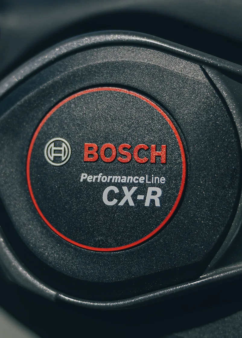 Motordeckel am CUBE AMS Hybrid 177 C:62 AT 600X 2027 in carbon´n´white aus der Nähe, schwarzer Deckel mit rotem Ring, darin das Bosch Logo und der Schriftzug Performance Line CX-R.