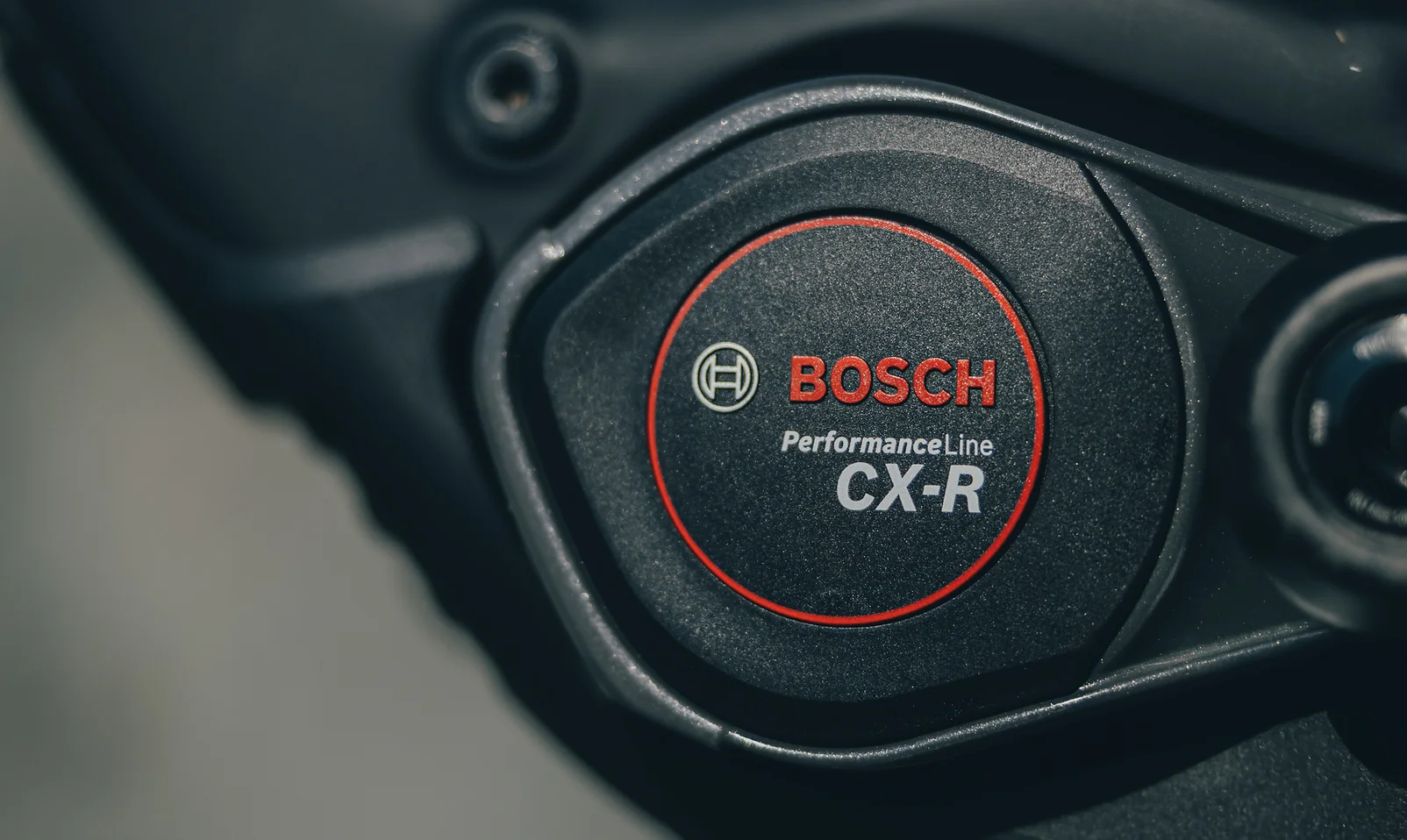 Motordeckel eines Bosch Performance Line CX-R aus der Nähe: schwarzes Gehäuse, rundes Emblem mit rotem Ring, darin das Bosch-Logo und der Schriftzug PerformanceLine CX-R