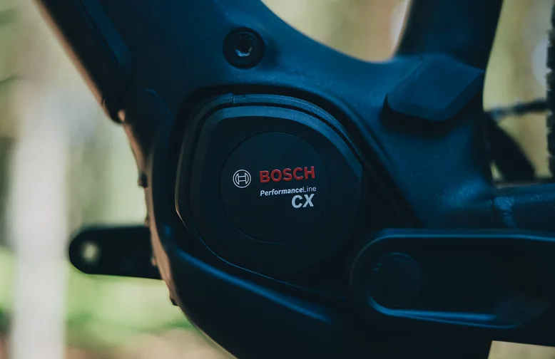 Motordeckel am CUBE Reaction Hybrid Pro 800 2027 in silverdust´n´prism aus der Nähe, auf dem schwarzen Deckel steht Bosch Performance Line CX, dahinter der dunkelgraue Rahmen, im Hintergrund unscharfes Grün.