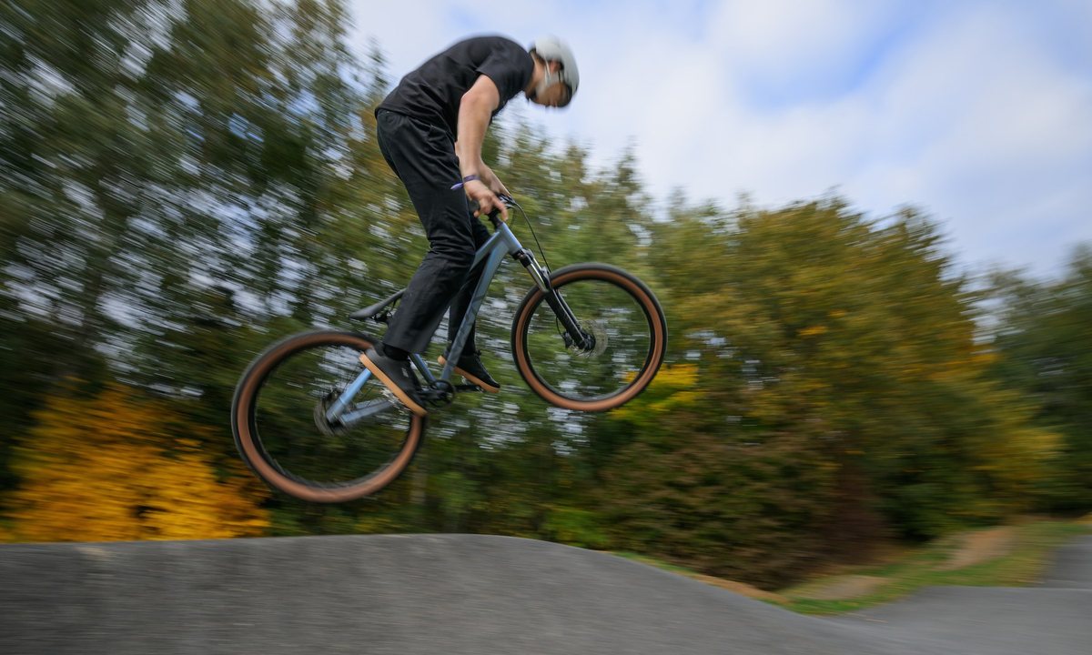 Fahrer springt mit einem CUBE Flying Circus Dirtbike über einen Pumptrack-Hügel