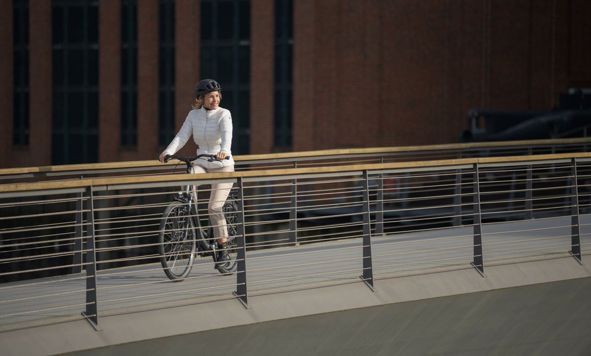 CUBE Town 2027: Fahrt über eine Fußgängerbrücke vor einer Backsteinfassade
