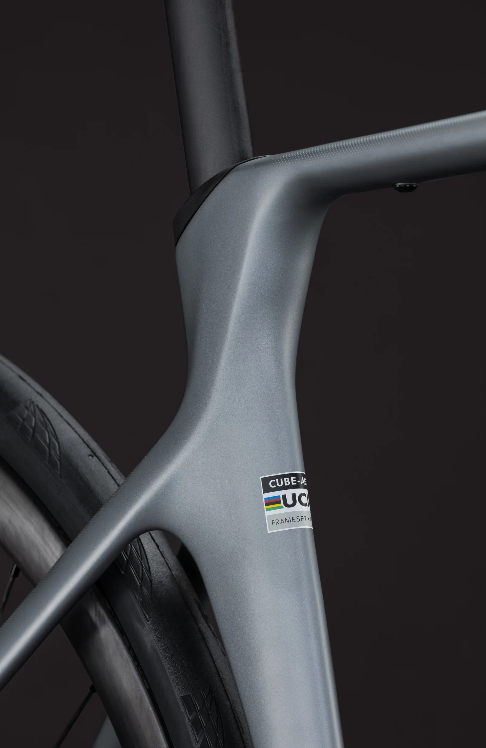 Steuerrohr und Unterrohr des CUBE Agree C:62 SLX 2027 in slategrey gehen ohne Kante ineinander über, am Unterrohr klebt der UCI-Aufkleber für den Rahmensatz, links daneben Reifen und tiefe Felge