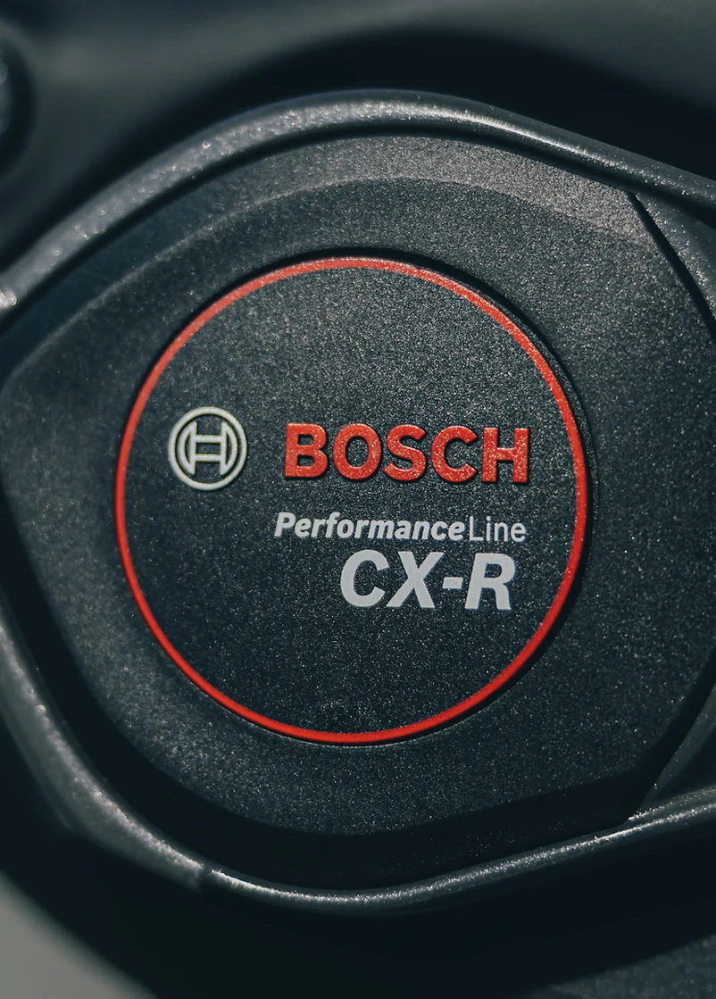 Motordeckel am CUBE AMS Hybrid 177 C:62 AT 2027 aus der Nähe: schwarzes Gehäuse, rundes Emblem mit rotem Ring, darin das Bosch-Logo und der Schriftzug Performance Line CX-R