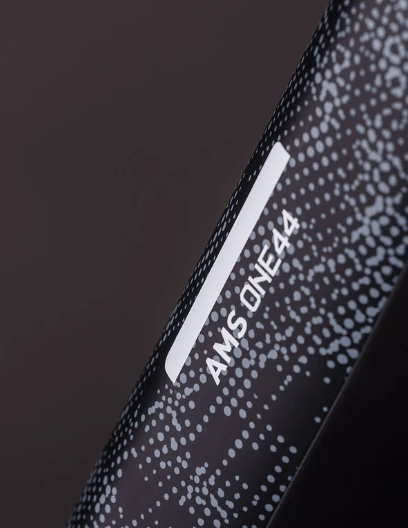 Unterrohr eines CUBE AMS Hybrid ONE44 C:68X SLT 2026 in matrixblack´n´white aus der Nähe: schwarzes Rohr mit hellem Punktmuster und dem weißen Schriftzug AMS ONE44, Studioaufnahme auf dunklem Grund