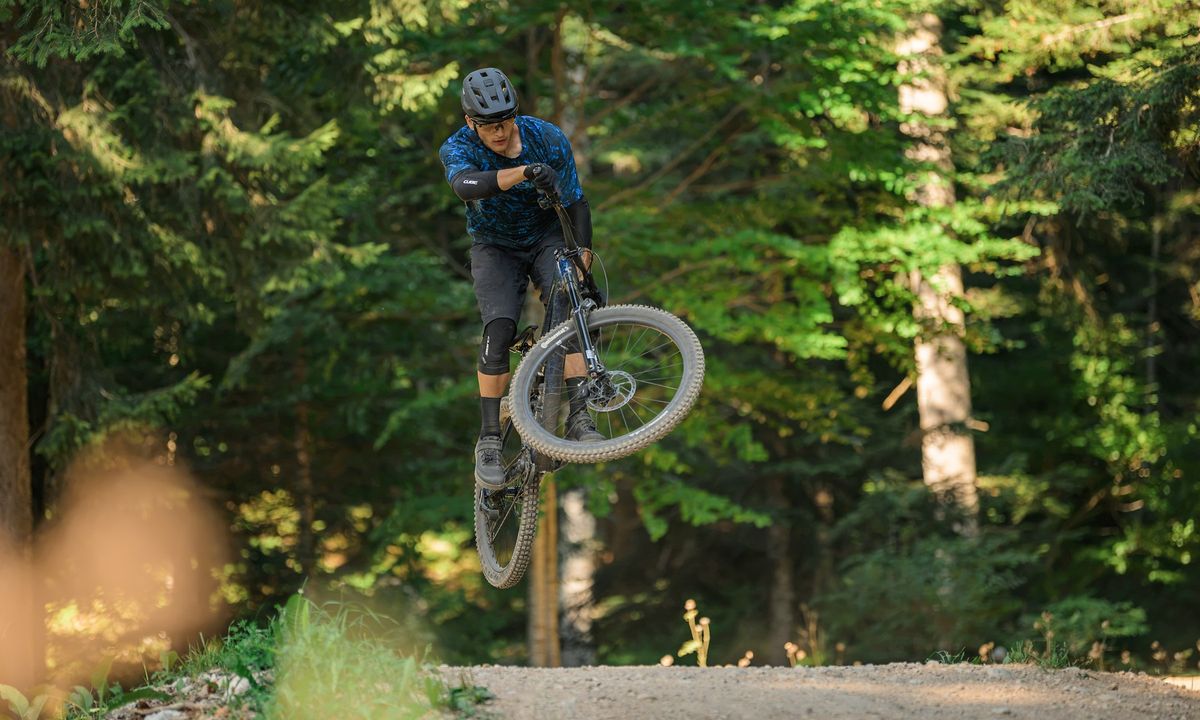 Mountainbiker auf einem CUBE Stereo Trail-Fully bei einem Sprung im Wald